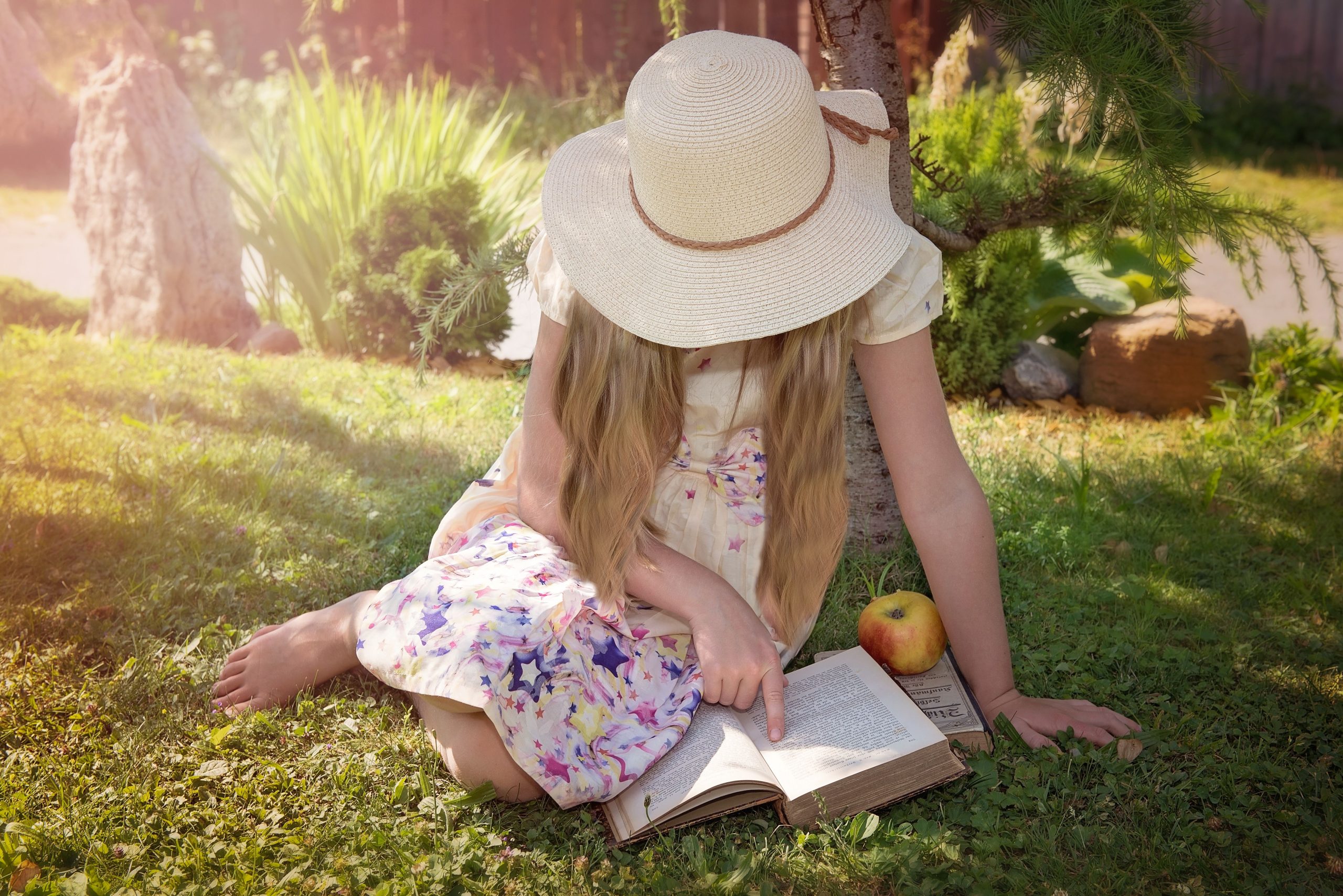 Young lady sitting in the grass reading a book